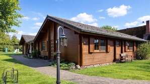 Une cabane en bois avec un toit en pente, une allée dallée et un petit jardin.
