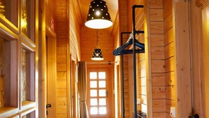 Un couloir en bois avec un luminaire suspendu, un porte-manteau et une porte dotée d’une fenêtre.