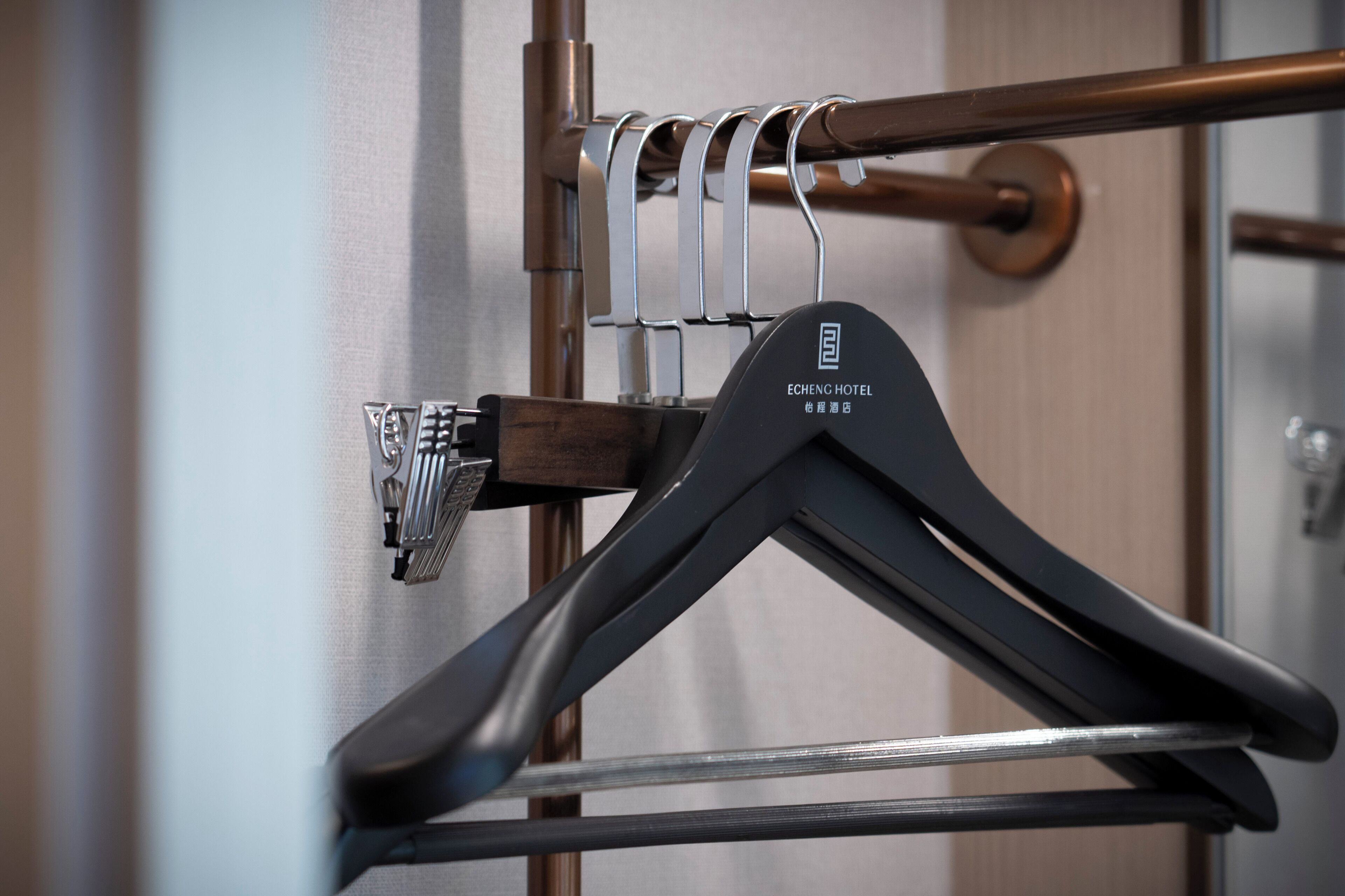 A hotel room with a wooden door, a radiator, and a black hanger with the hotel name on it.
