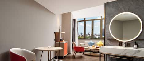 Une salle de bain d’hôtel moderne, dotée d’un grand miroir, d’un lavabo avec un plan de travail en marbre et d’un porte-serviettes rouge.
