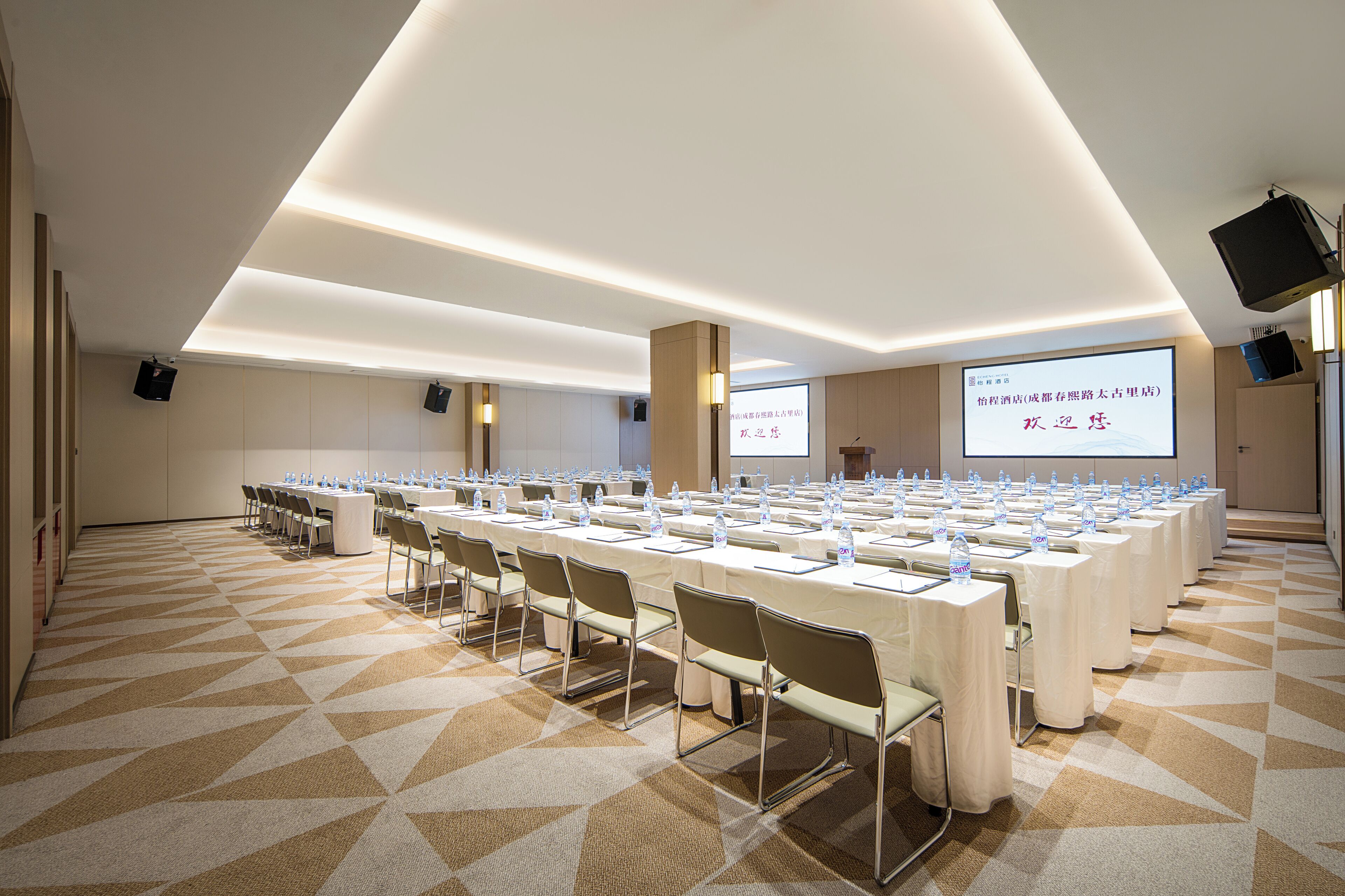Une salle de conférence équipée de plusieurs tables, de chaises et d’un écran de projection.