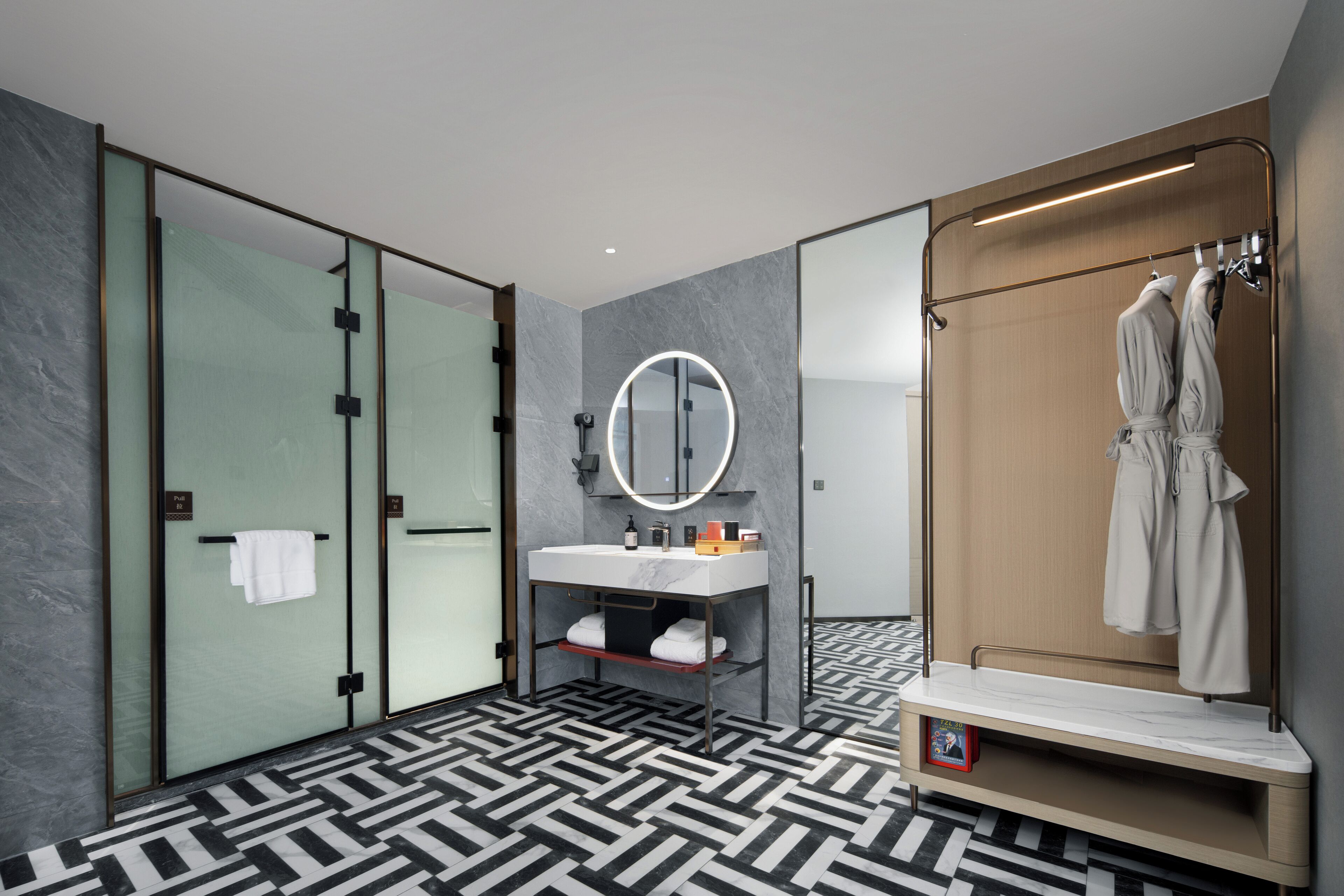 A modern bathroom with a large mirror, a sink, and a robe rack.