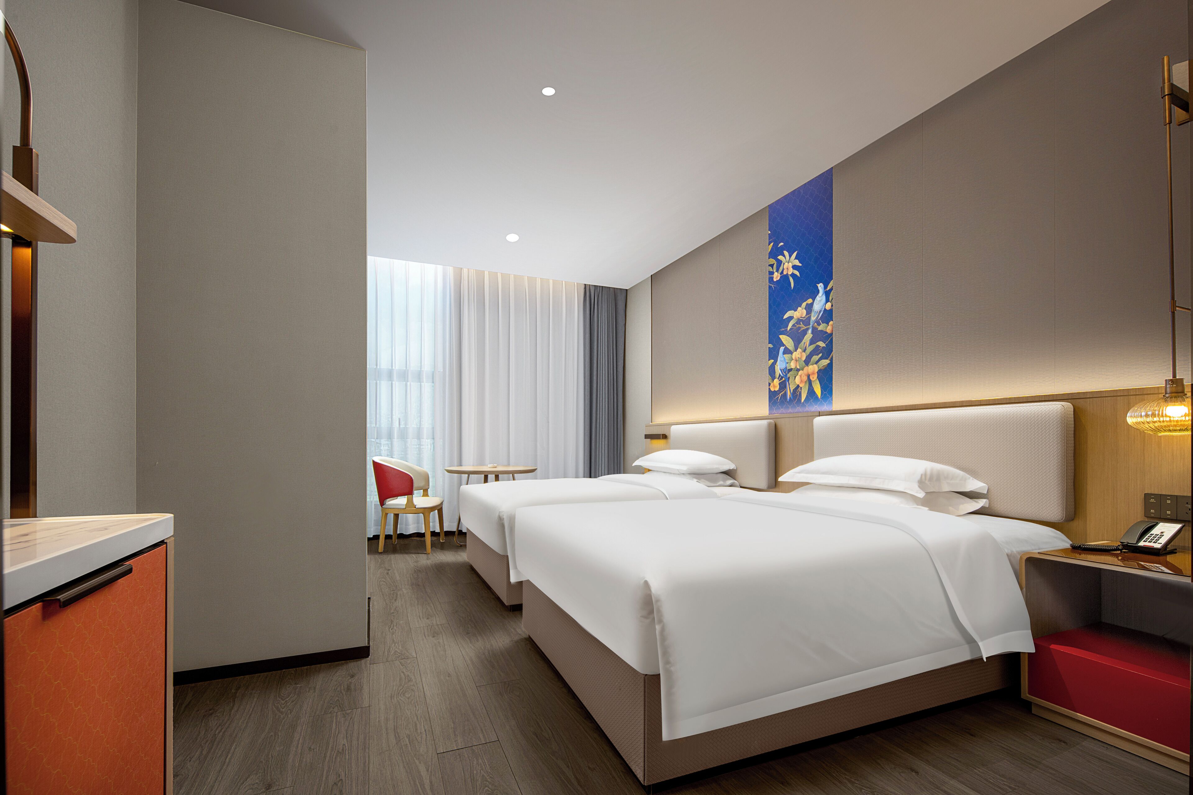 A hotel room with two beds, a desk, a chair, and a small table.