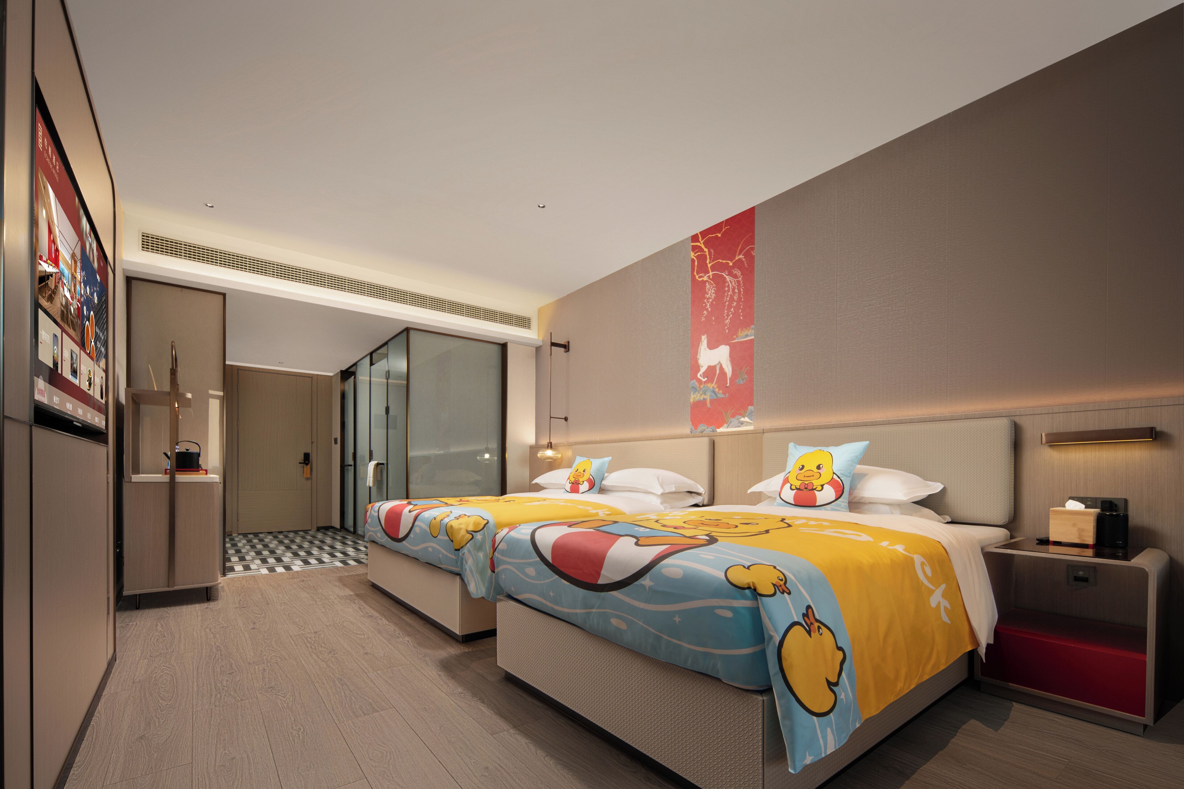 A hotel room with two beds, a minibar, a desk, and a large window.
