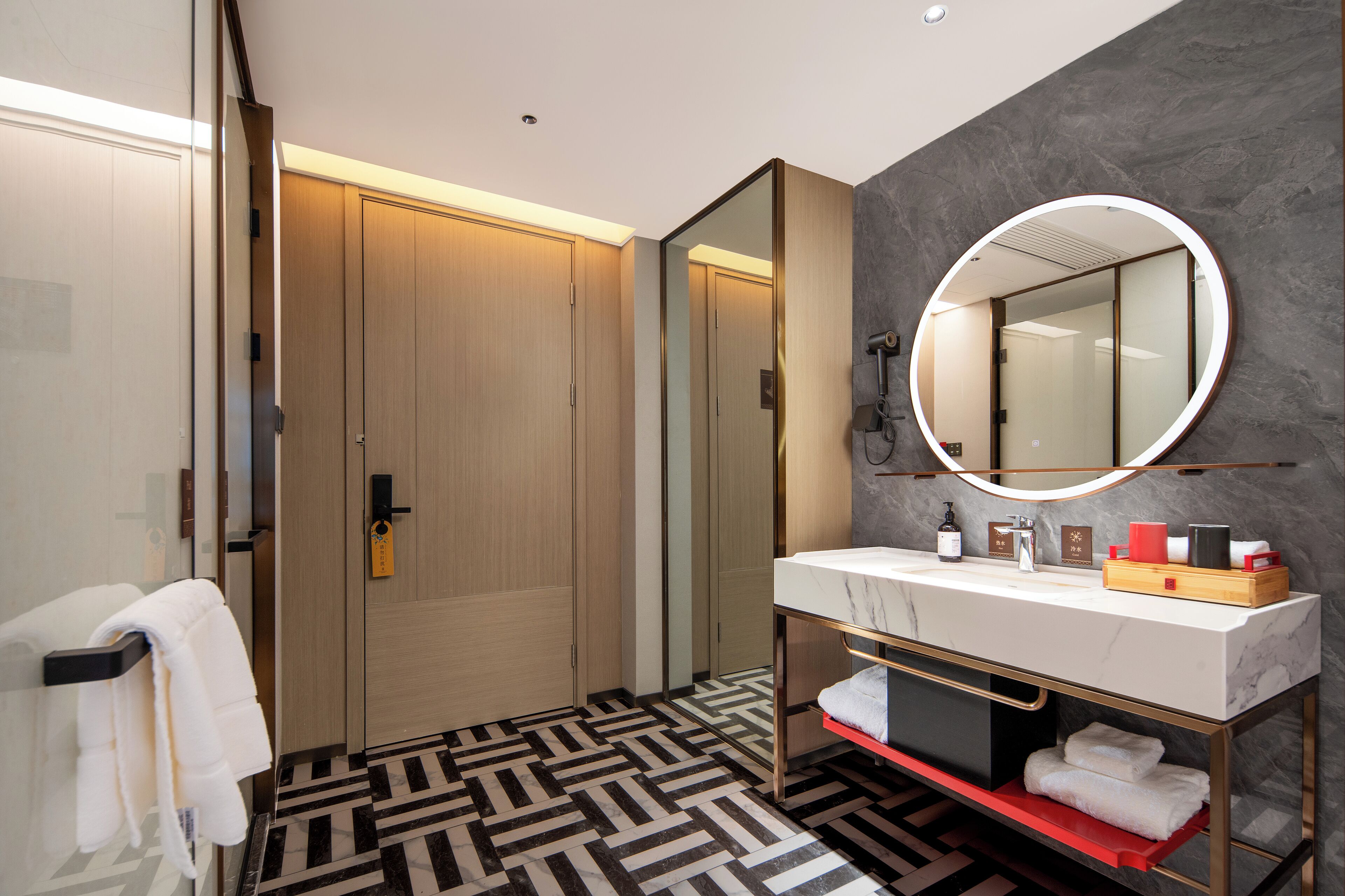 Un baño moderno con un lavamanos de mármol, un espejo grande y un suelo estampado.