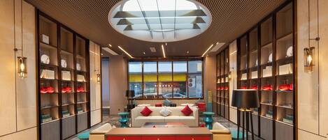 A modern interior with a central sofa, shelves with shoes, and a large window with a view of the street.