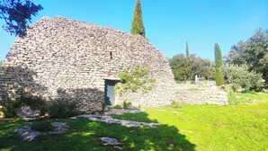 A stone structure with a small entrance, surrounded by greenery and trees. - Le Mas Natán Au Coeur du luberon Gordes (Gordes)