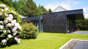 A modern house with a well-maintained lawn and a patio area. - "Das Vosshörn - Steuermann" - designer vacation apartment with two terraces (Cuxhaven)