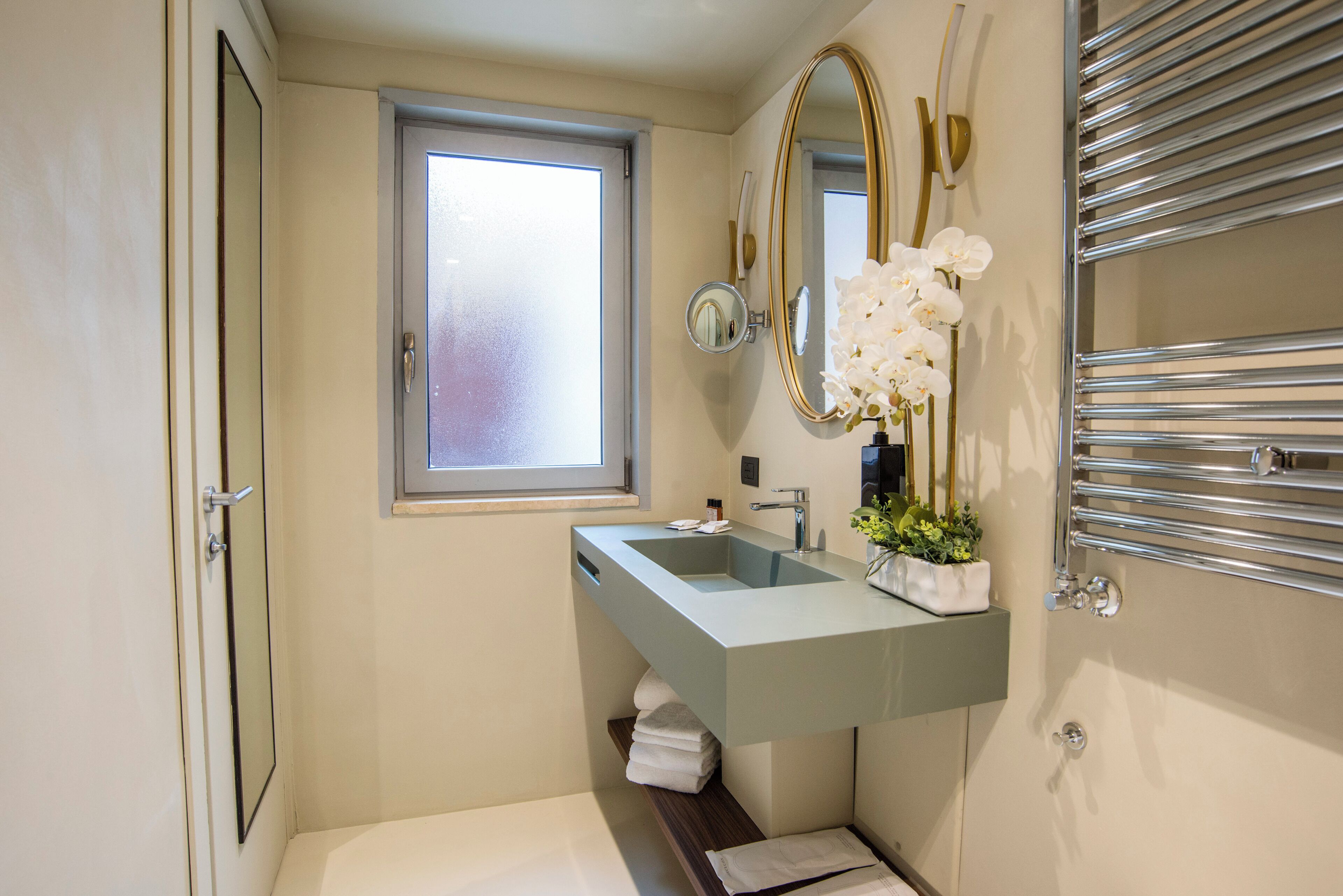 Un baño moderno con lavamanos integrado, un espejo grande, una ventana y un perchero para toallas.