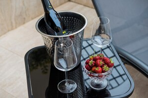 A table with a wine bottle, two glasses, and a bowl of strawberries. - Bocca di Leone Luxury Suite (Rome)