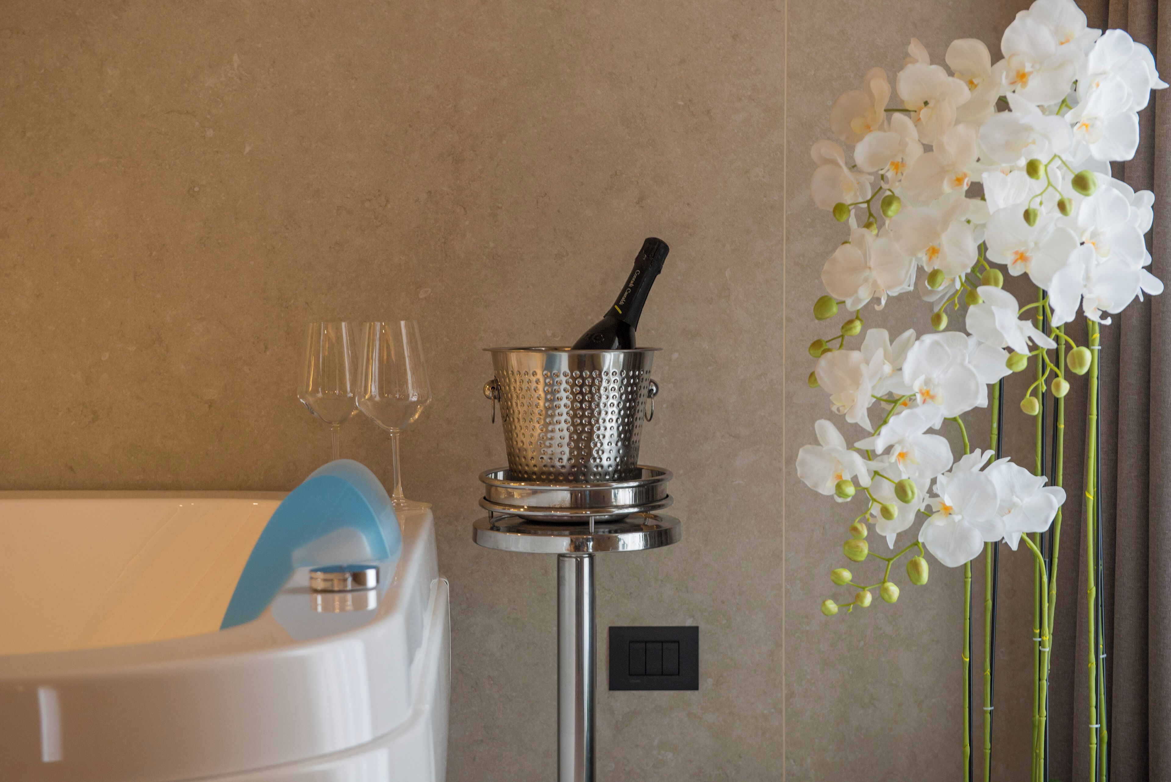 Ein Badezimmer mit einer Badewanne, einem Sieb mit einer Flasche und einer Vase mit weißen Orchideen.