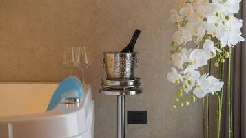 Ein Badezimmer mit einer Badewanne, einem Sieb mit einer Flasche und einer Vase mit weißen Orchideen.