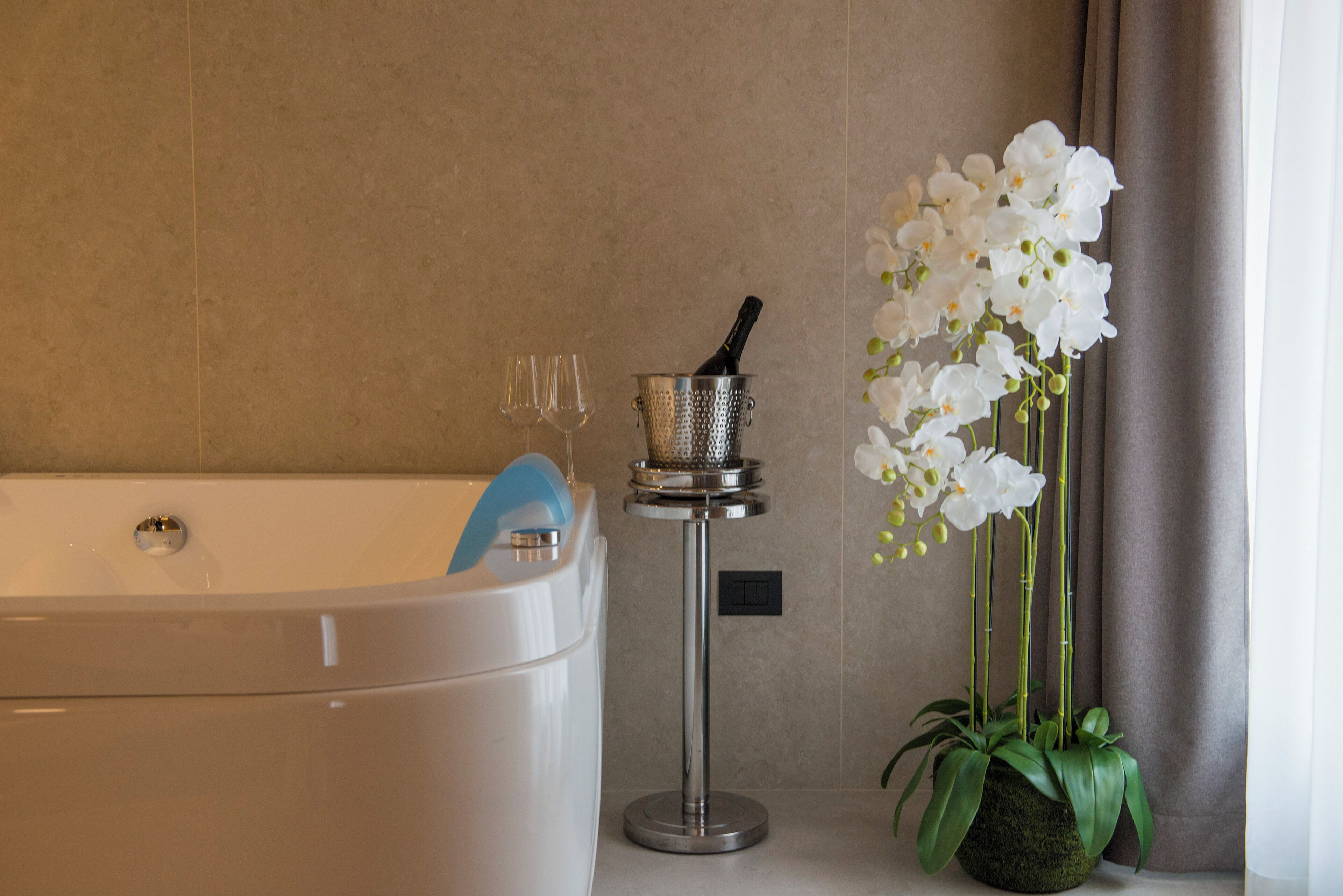 Un baño con una bañera, una botella de champán y una orquídea en maceta.