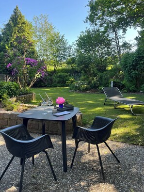 An outdoor patio with a table and chairs, surrounded by lush greenery and a trampoline. - "Gästehaus am Brockeswald" - your retreat in the countryside (Cuxhaven)