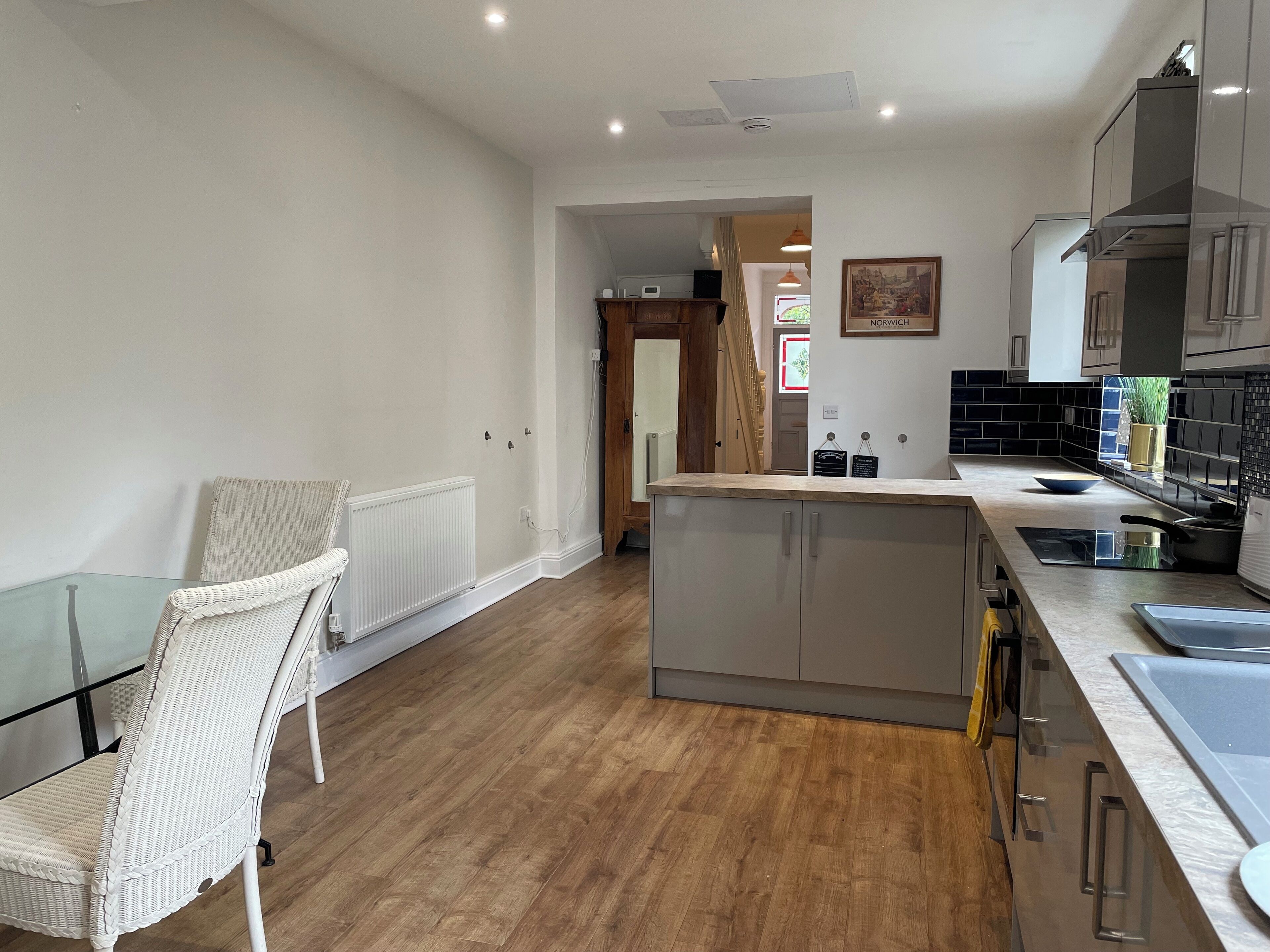 A modern kitchen with a central island, stainless steel appliances, and a glass dining table.