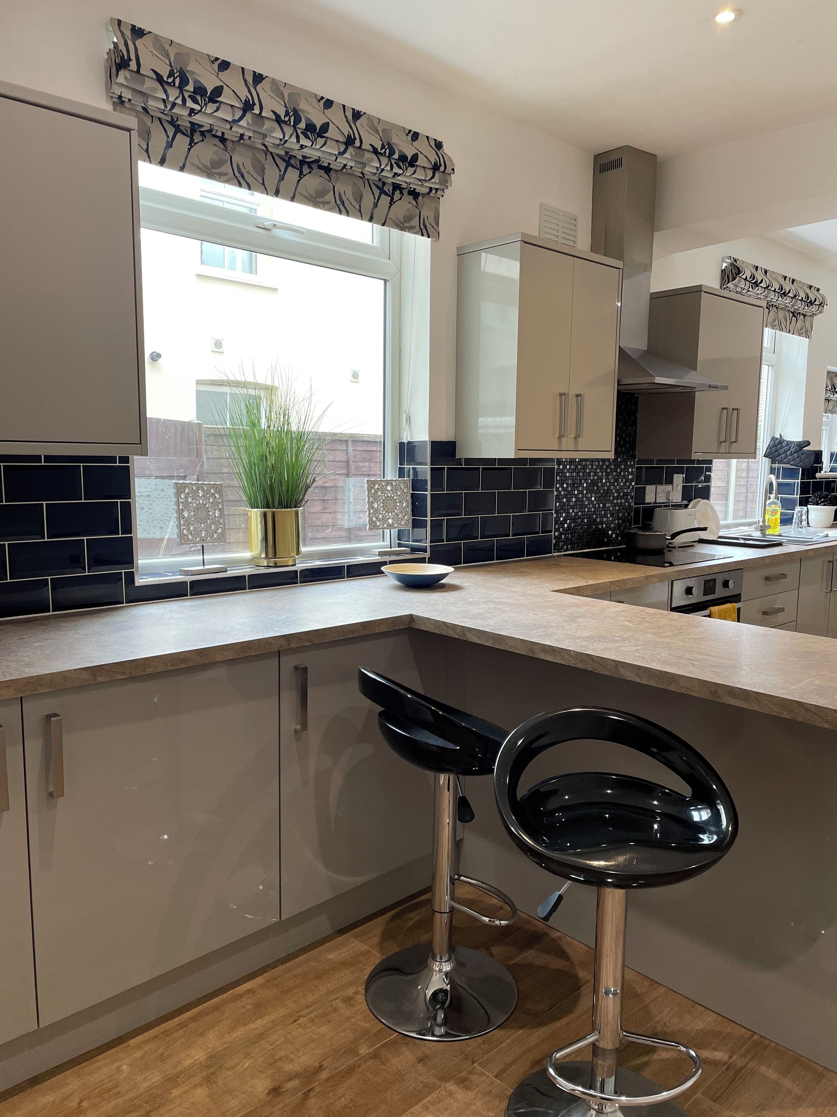 A modern kitchen with a bar stool, a window with a view, and a tiled backsplash.