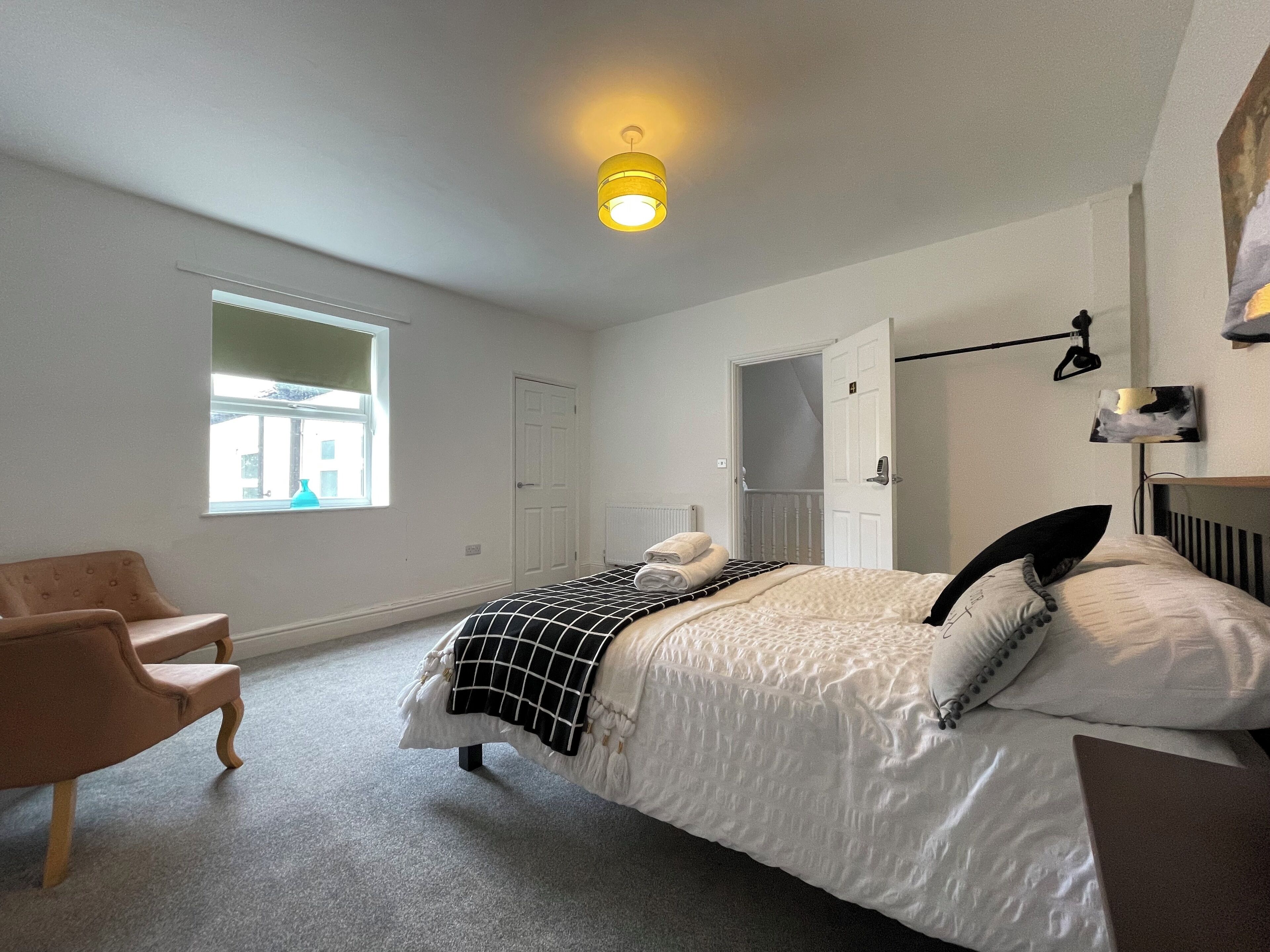Ein Schlafzimmer mit einem Bett, einem Sessel, einem Fenster und einer Tür.