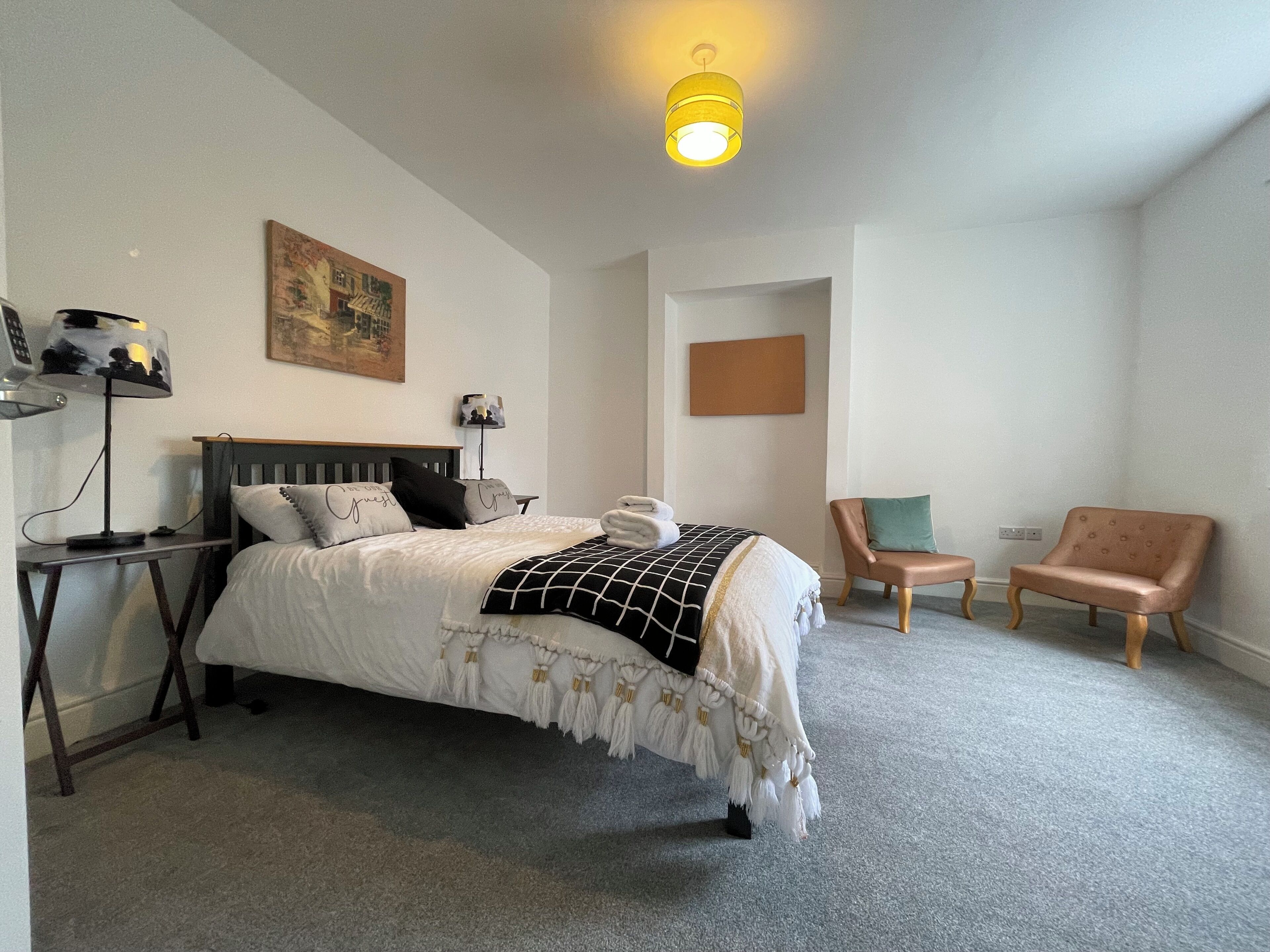 A neatly arranged hotel room with a bed, a desk, a chair, and a lamp.