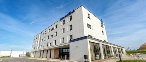 Un moderno edificio de hotel con techo plano, múltiples ventanas y un cartel que dice "HOTEL AKENA".