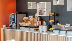 A buffet setup with various food items, a coffee machine, and decorative plants.