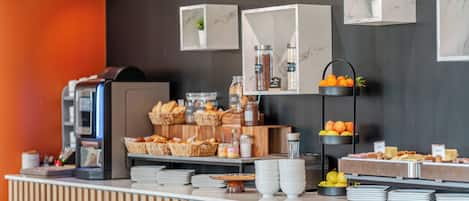 A buffet setup with various food items, a coffee machine, and decorative plants.
