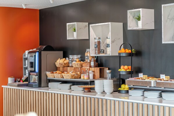 A buffet setup with various food items, a coffee machine, and decorative plants. - Hôtel Akena Châlons en Champagne (Châlons-en-Champagne)