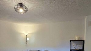 A modern living room with a sectional sofa, a coffee table, a floor lamp, and a shelving unit with decorative items.
