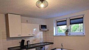 A compact kitchen with white cabinets, a microwave, a sink, and a small dining area with a table and chairs.