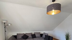 Una sala de estar moderna con un sofá modular, una mesa de centro negra y una lámpara colgante.