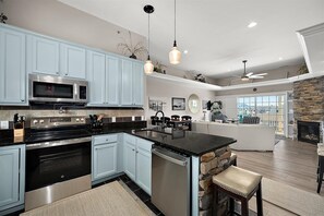 A modern kitchen with light blue cabinets, stainless steel appliances, and a central island. - Downtown Condo with Great Views and Prime Location (Ocean City)