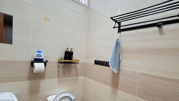 Un baño moderno con inodoro, bidé, lavamanos y un perchero para toallas.