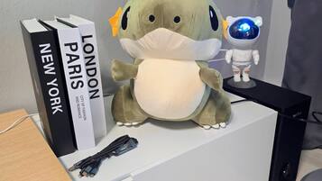 A plush toy dinosaur, a projector screen, and books on a white table.