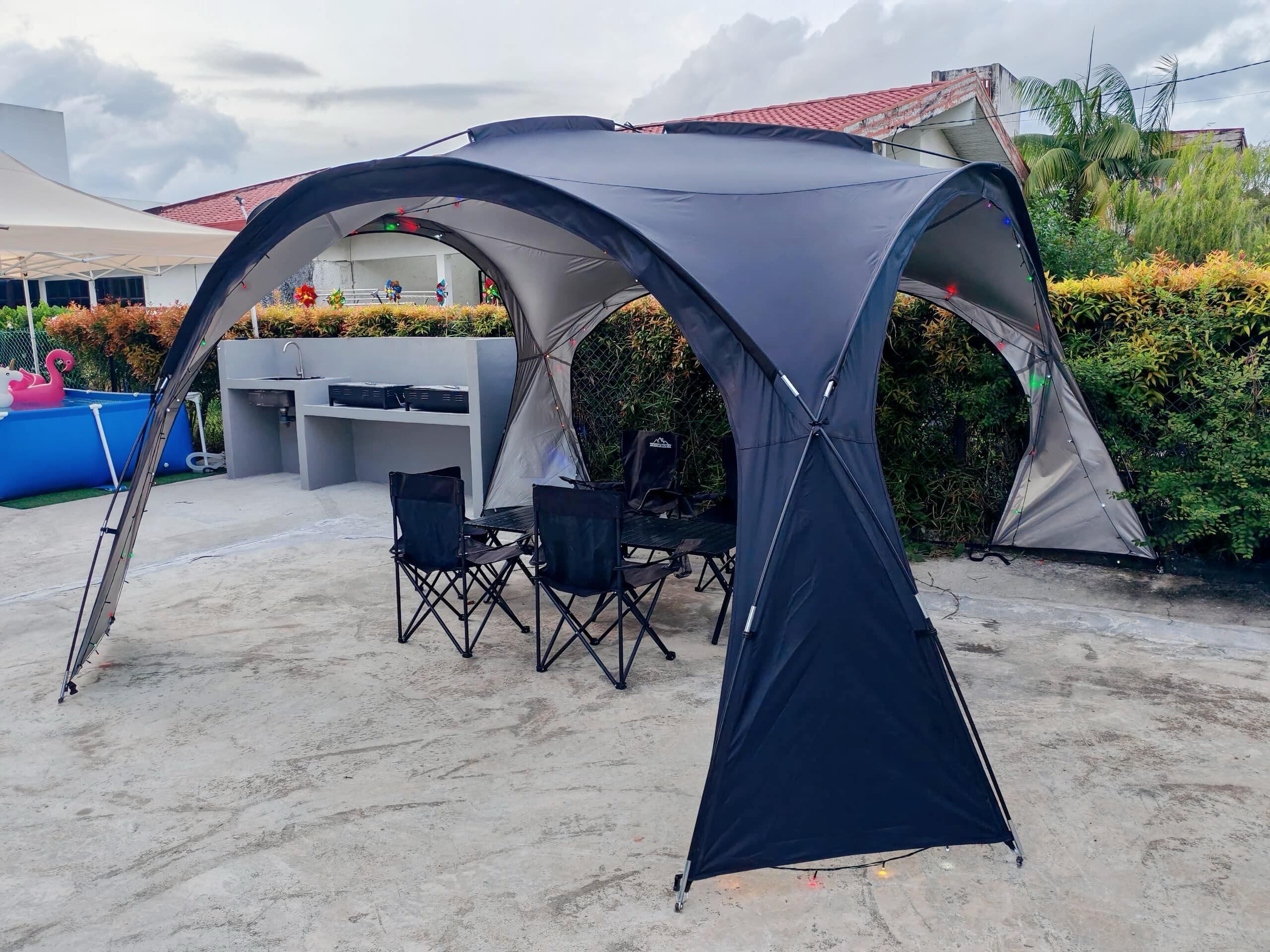 A tent with a table and chairs set up in an outdoor area.
