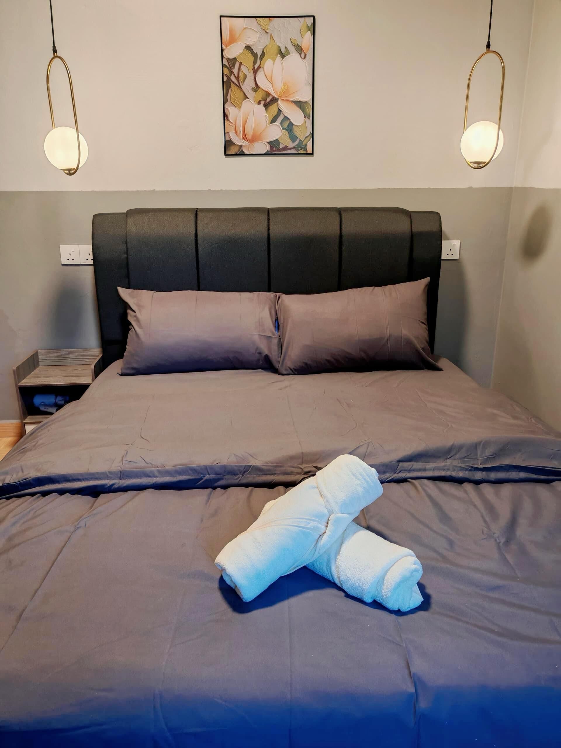 Una cama bien hecha con un cabecero oscuro, dos mesitas de noche y un cuadro colgado en la pared.