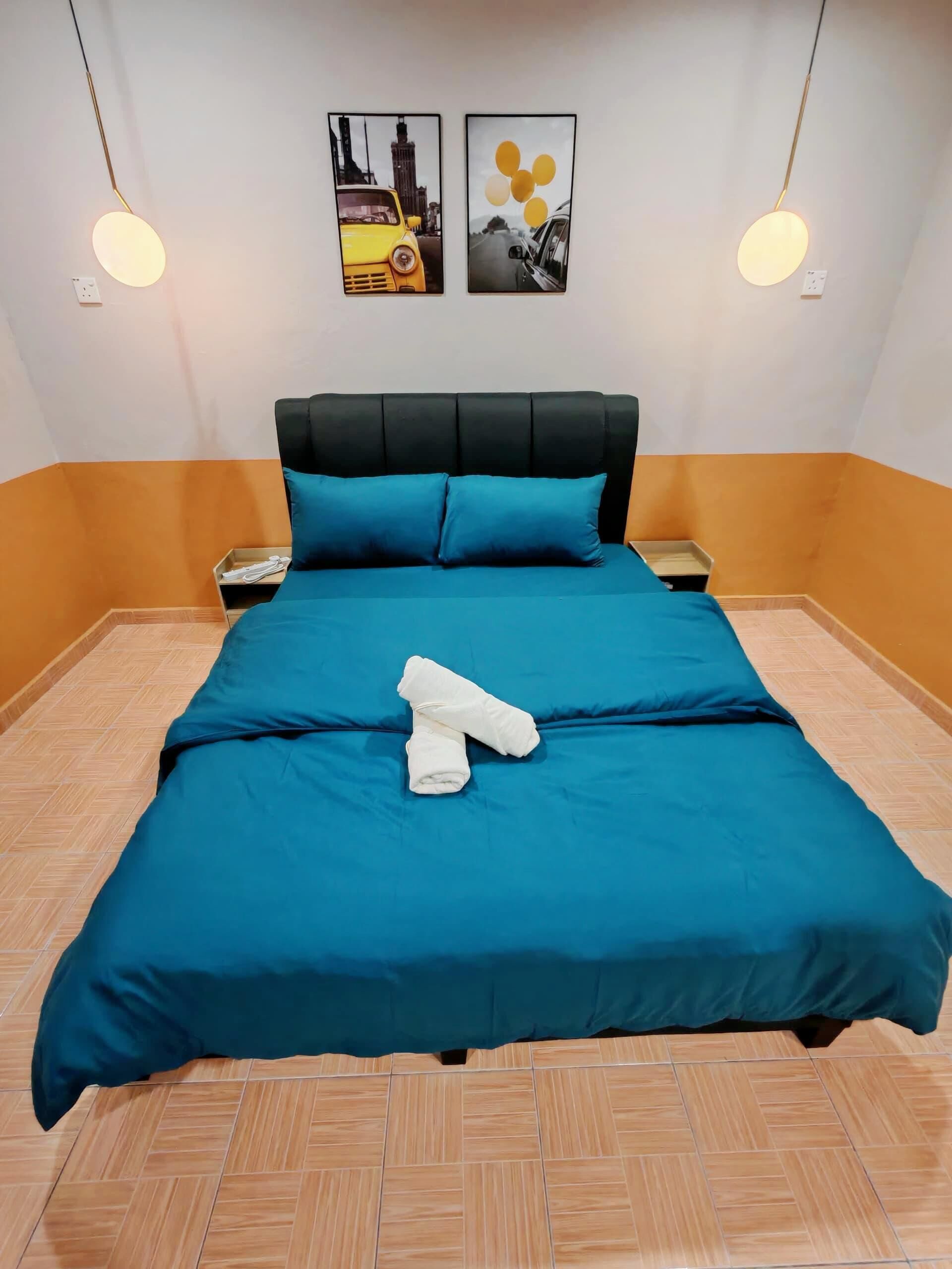 A hotel room with a bed, two nightstands, a black headboard, and two wall art pieces.
