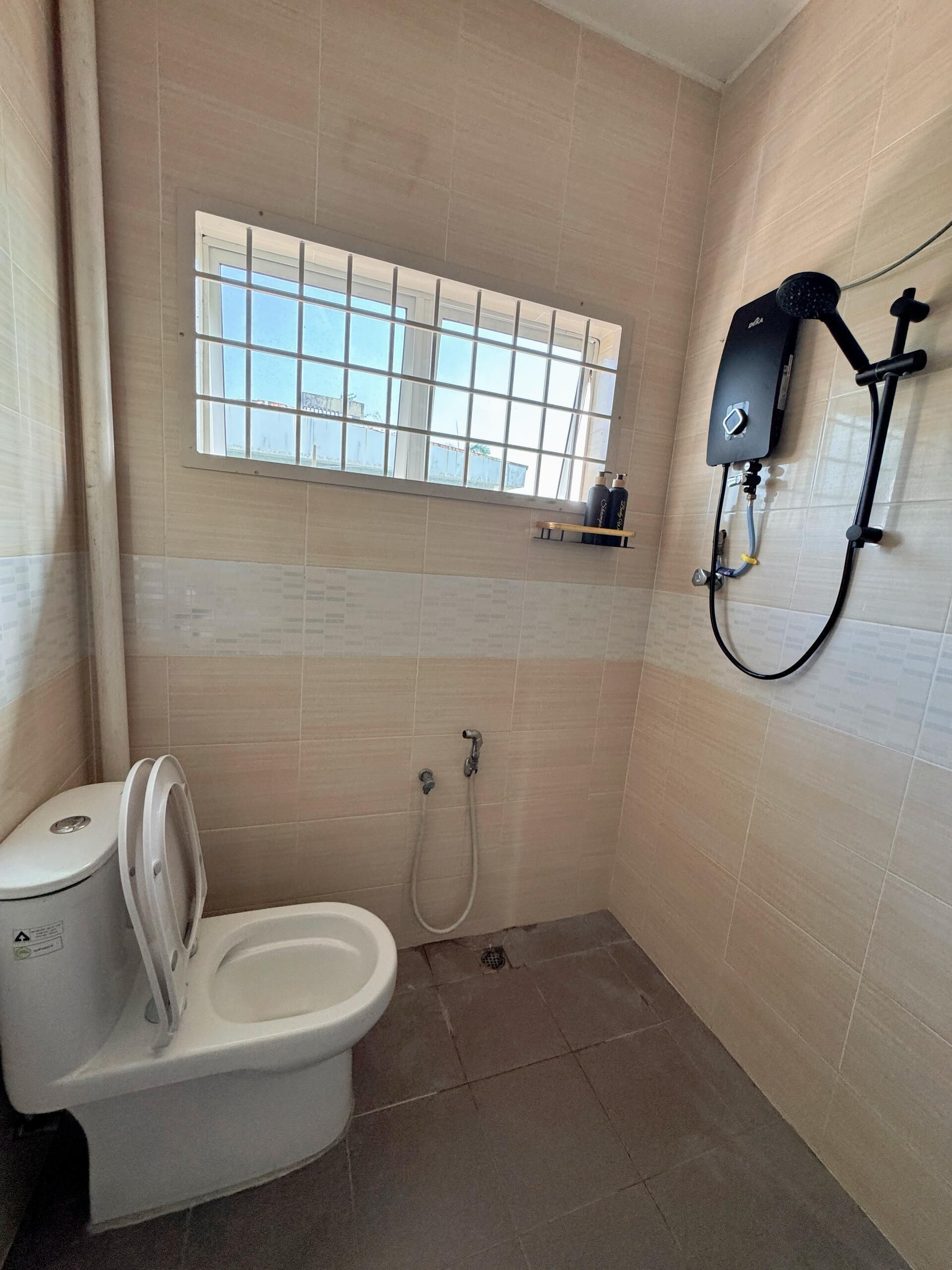 Un baño pequeño con inodoro, ducha y ventana.