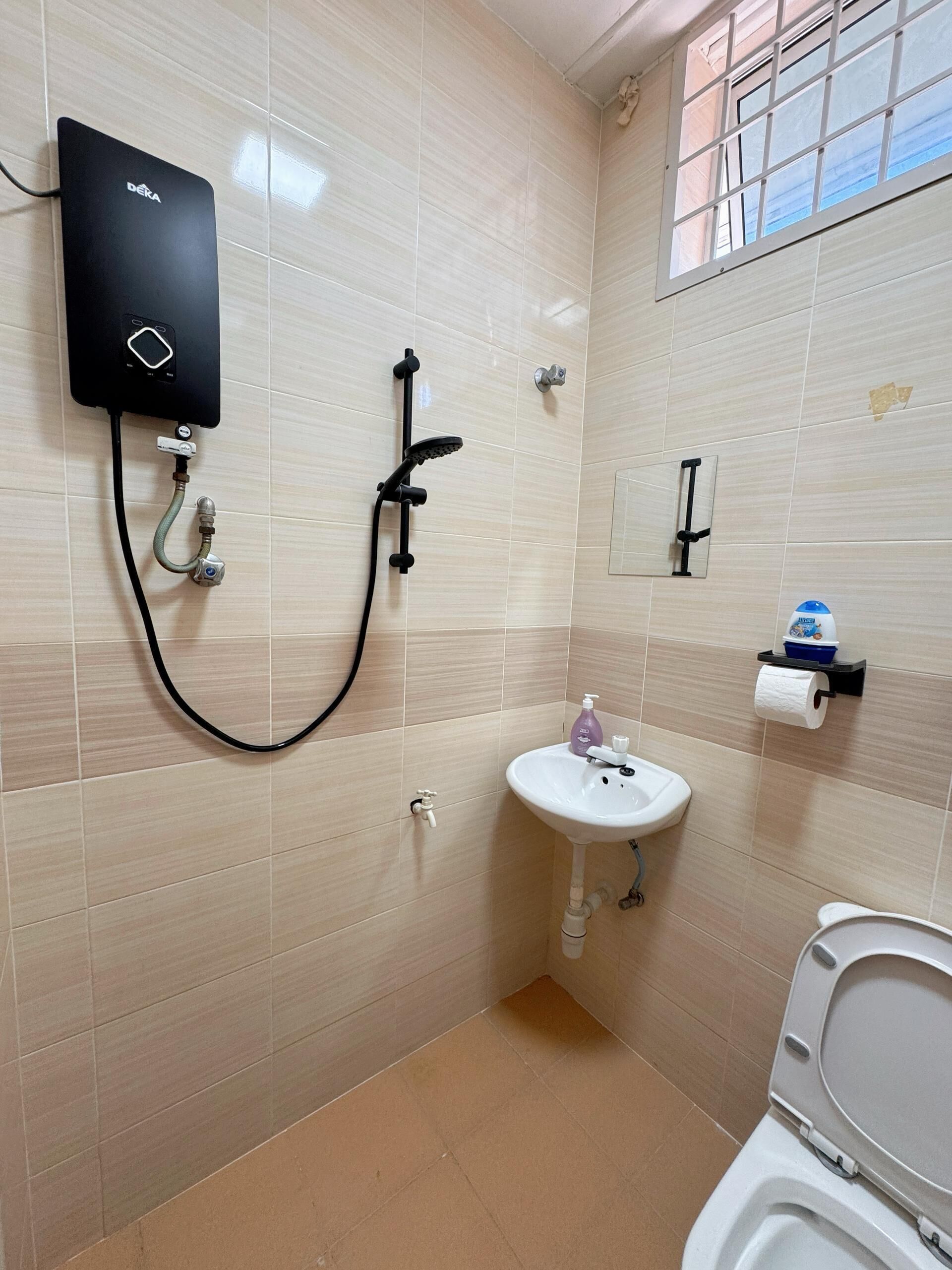 A bathroom with a DEKA shower unit, a sink, and a toilet.