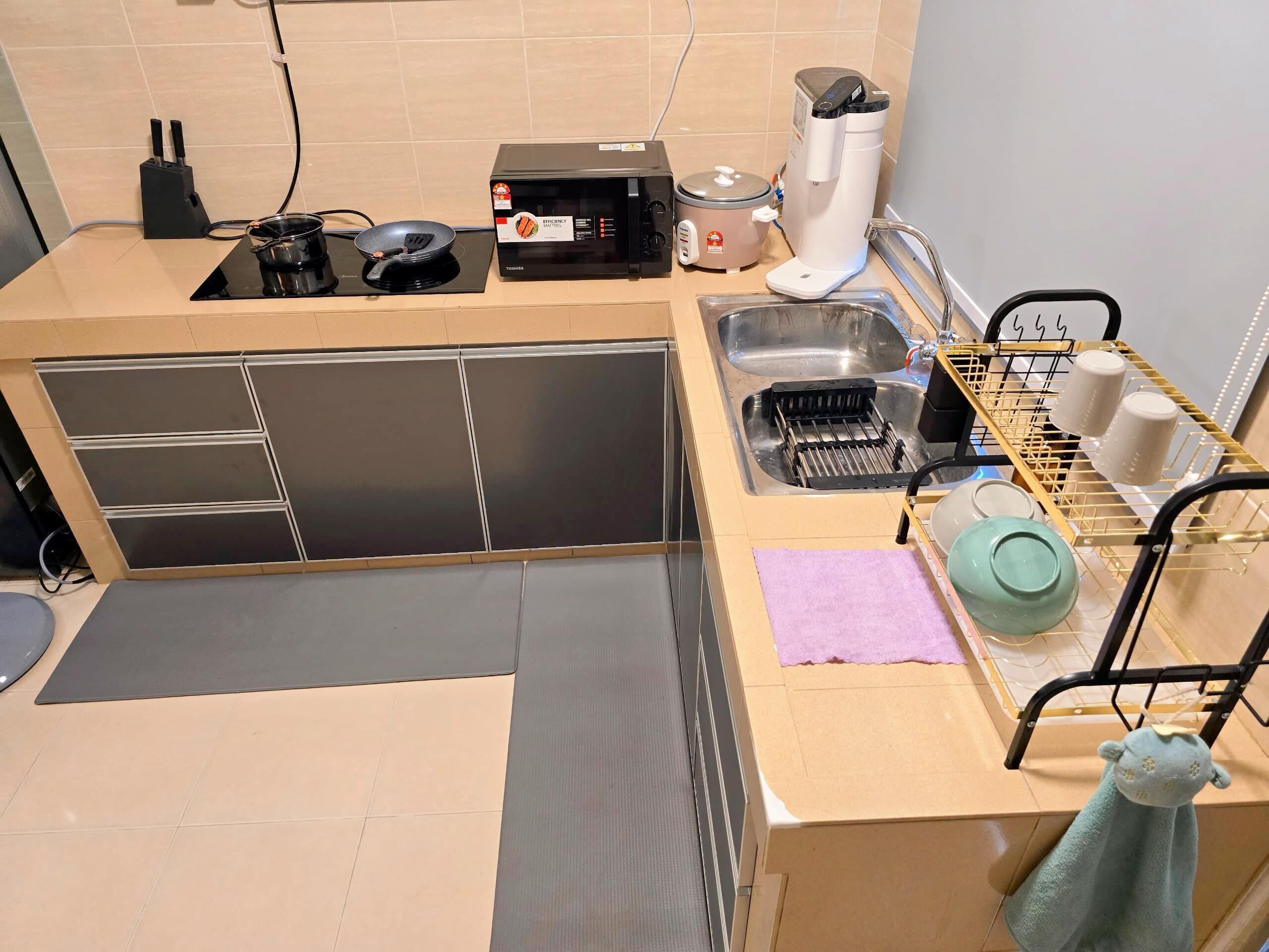 Una cocina compacta con pileta, estufa y una cocedora de arroz.