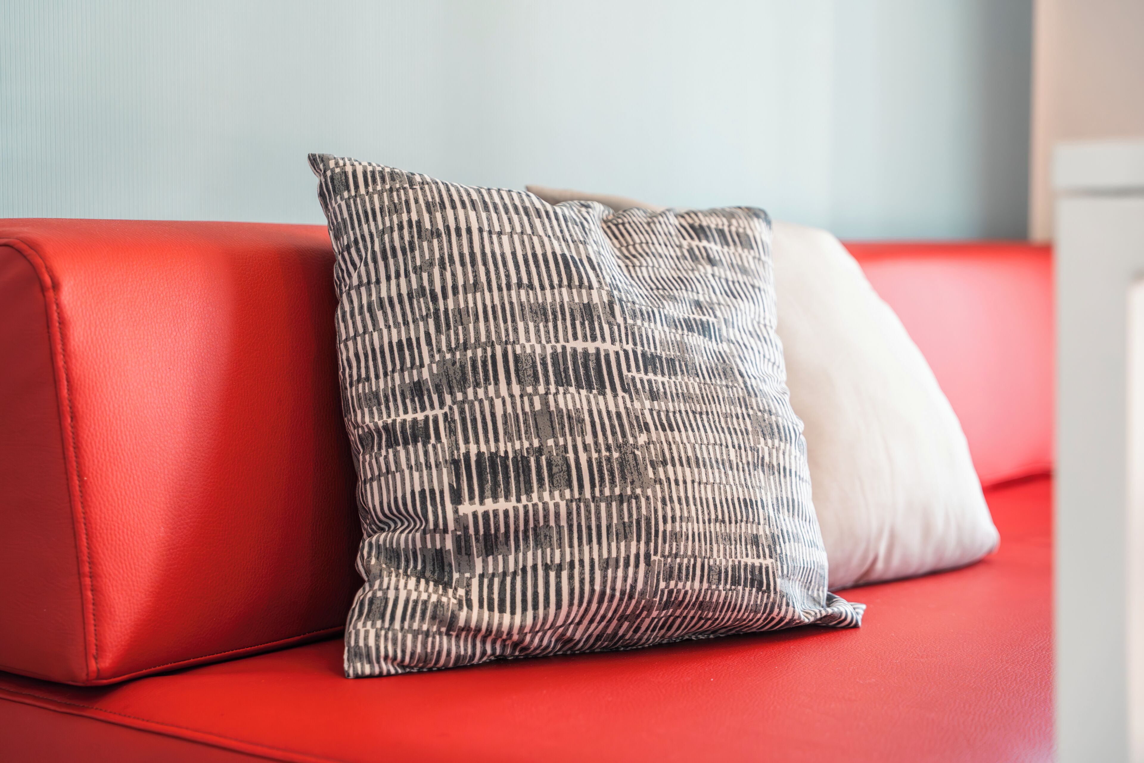 Un sofá rojo con dos almohadones, uno a rayas y otro liso.
