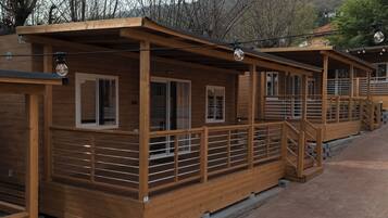 A row of wooden cabins with a covered walkway, wooden railings, and a brick pathway.