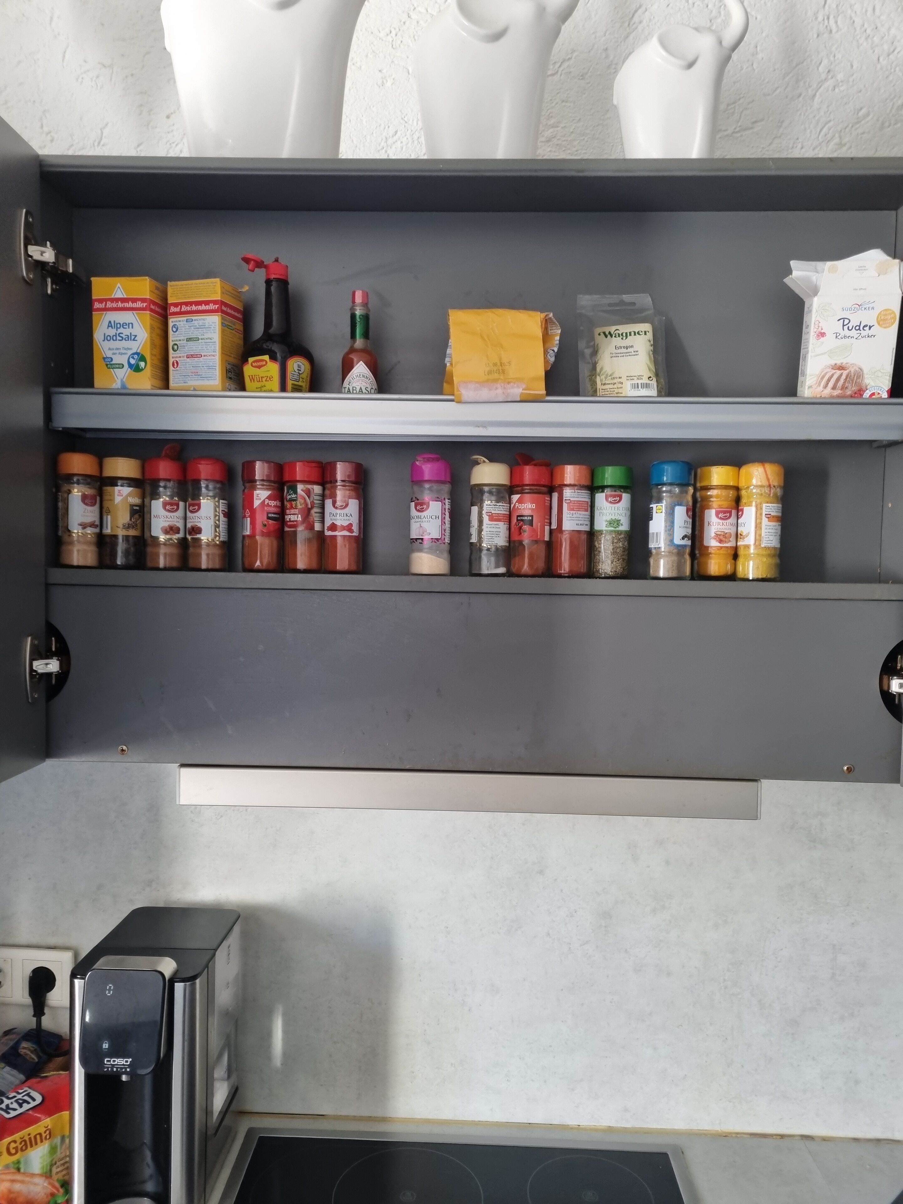 A kitchen with a built-in spice rack, a coffee machine, and a toaster.