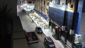 A street view at night with parked cars, a building with a sign 'Hotel Plaja', and a visible balcony with a plant. - HOUCINE APARTMENT (Aïn El Turk)