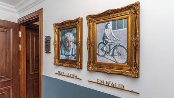 Two framed artworks on a wall with a blue and white color scheme, and a wooden door with a number plate.