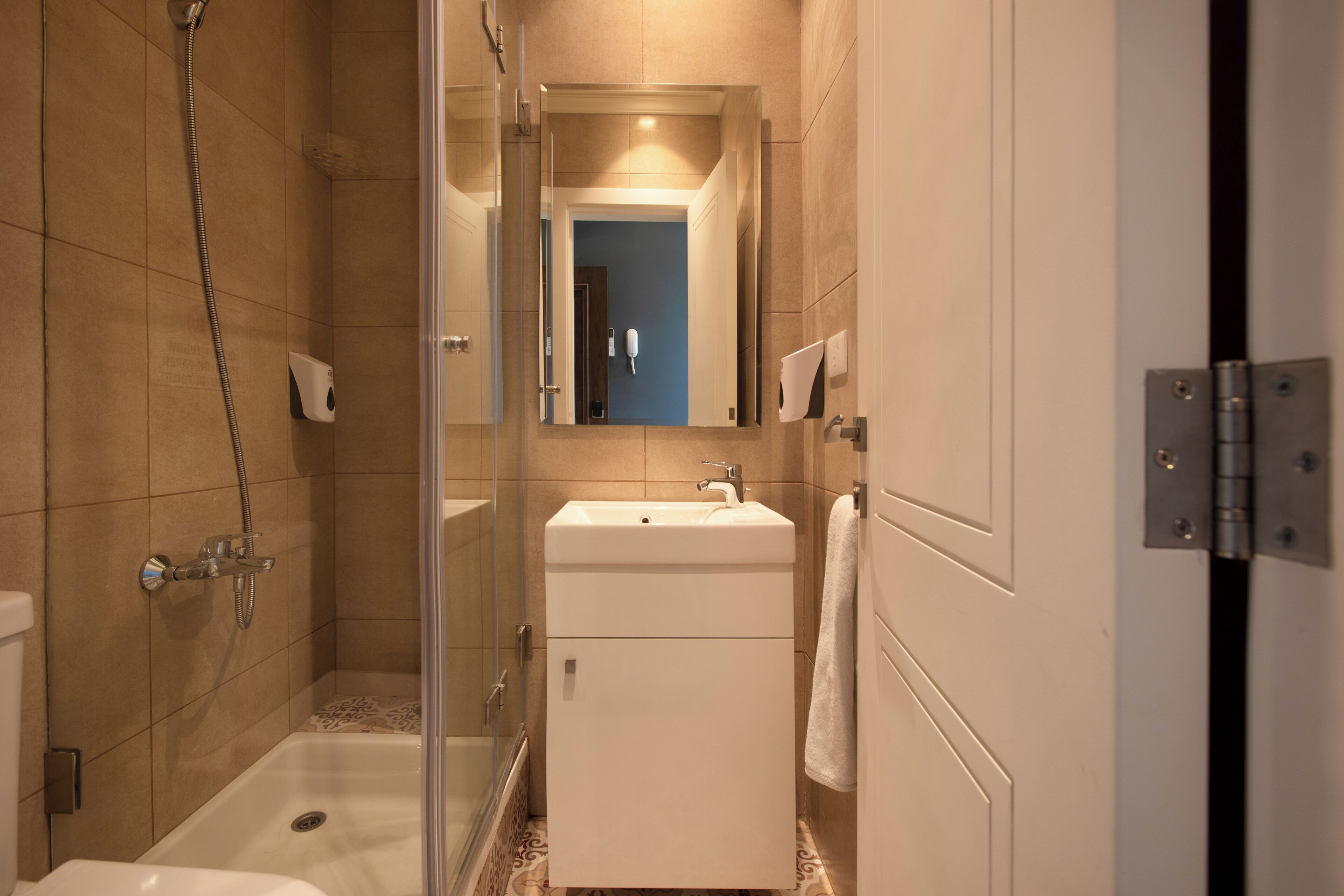 A bathroom with a glass-enclosed shower, a white sink, and a mirror above it.