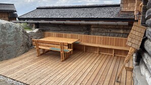 A wooden deck with a bench and table, surrounded by stone walls and a building with a sloped roof. - Lovely apartment for 4 guests with WIFI, TV, pets allowed and panoramic view (Forstau)