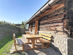 A rustic log cabin with a stone foundation, wooden benches, and a clear view of the surrounding landscape. - Nice apartment for 4 guests with WIFI, TV, pets allowed and panoramic view (Forstau)