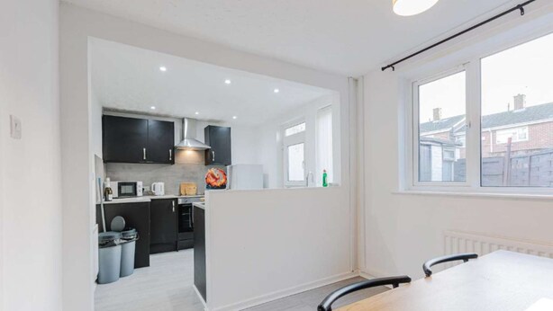 Cocina moderna con armarios oscuros, un microondas y ventana con vistas a un barrio residencial.