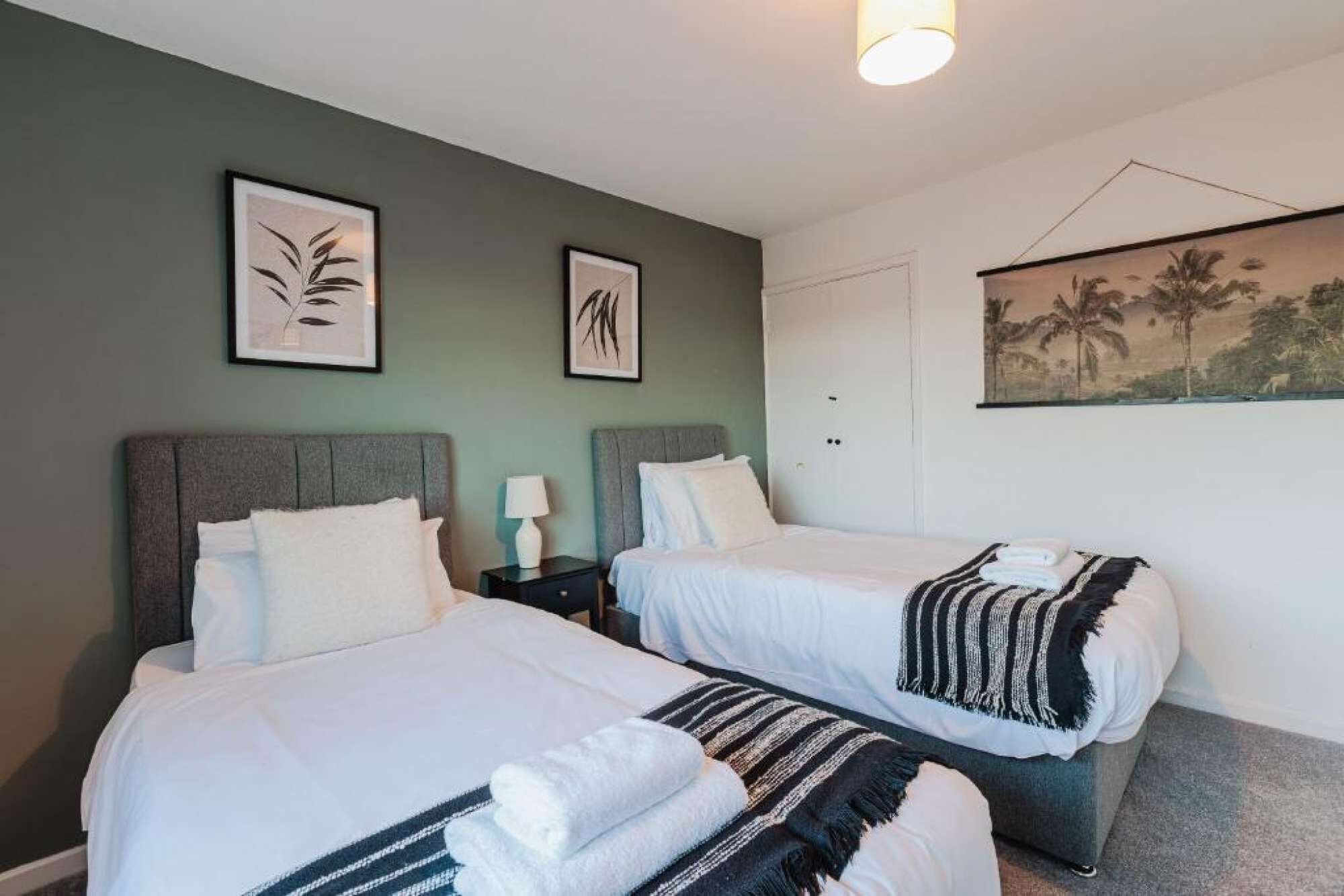 Ein Hotelzimmer mit zwei Betten, einem Nachttisch mit Lampe und Bildern an den Wänden.
