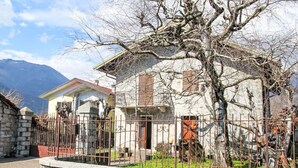 A stone-walled building with a metal fence, a balcony, and a view of mountains.