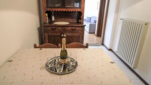 A dining table with a bottle of champagne, a tray with glasses, and a cabinet with dishes.